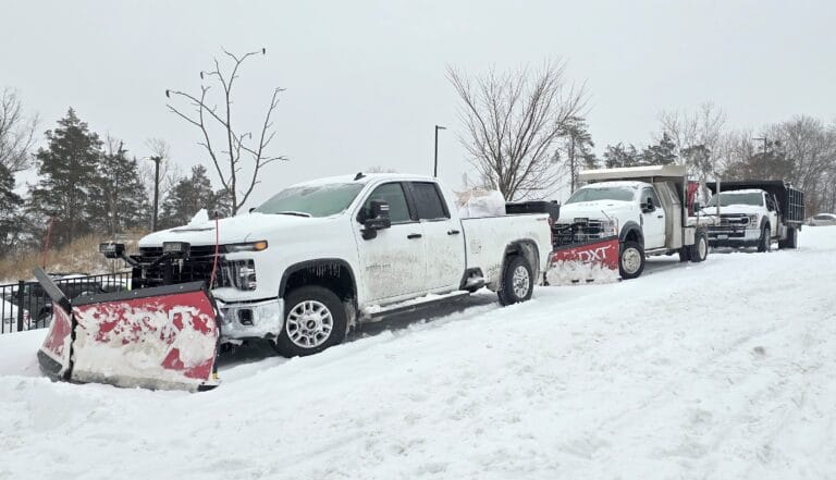 Snowplow trucks clearing snow-covered road in winter.
