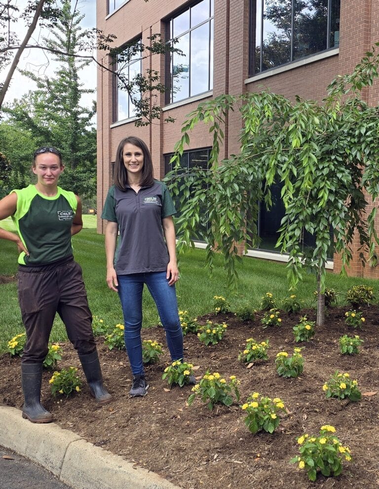 Two women standing in landscaped garden outside office building