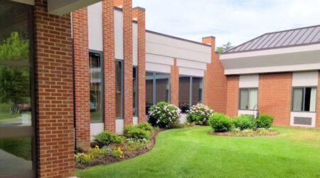 Red brick building with green landscaped garden.