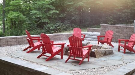 Red chairs around stone fire pit on patio.