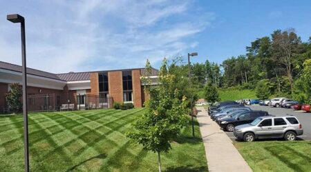 Building with parking lot and green lawn.